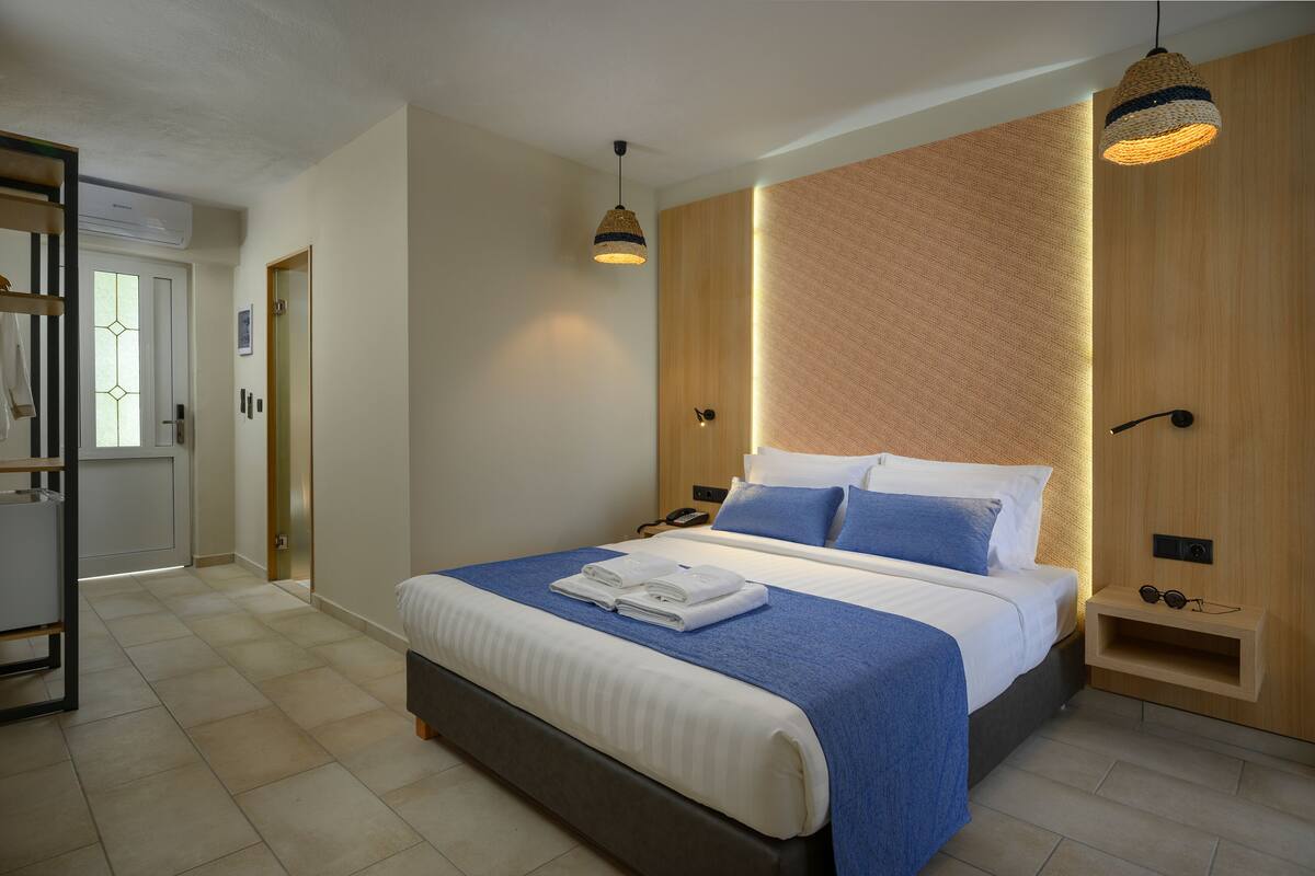 A modern bedroom with a large bed, a bedside table, a wardrobe, and a hanging light fixture.