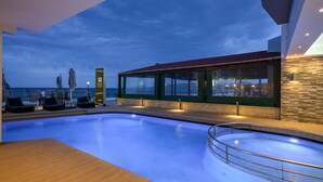 A swimming pool with lounge chairs and a view of the sea at dusk. - Mare Boutique - Adults Only (Apokoronas)