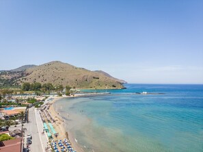 A coastal area with a beach, clear blue waters, and a hilly landscape in the background. - Mare Boutique - Adults Only (Apokoronas)