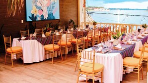 A long dining table set with chairs, a large painting on the wall, and a view of the water outside. - Hotel Casona de La Isla (Flores)