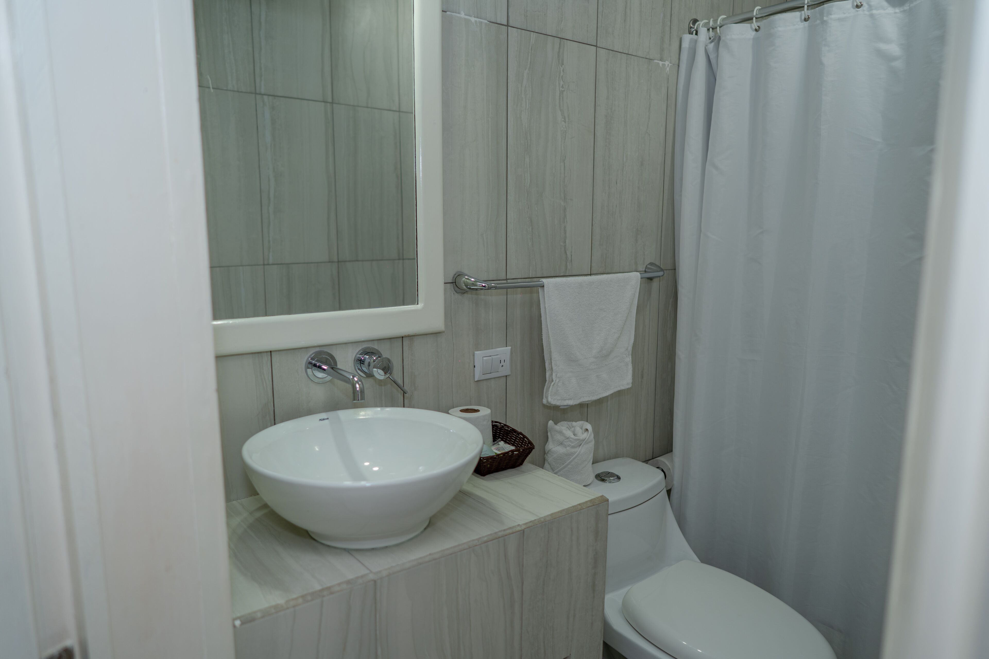 Un baño con lavamanos, espejo y retrete blancos.