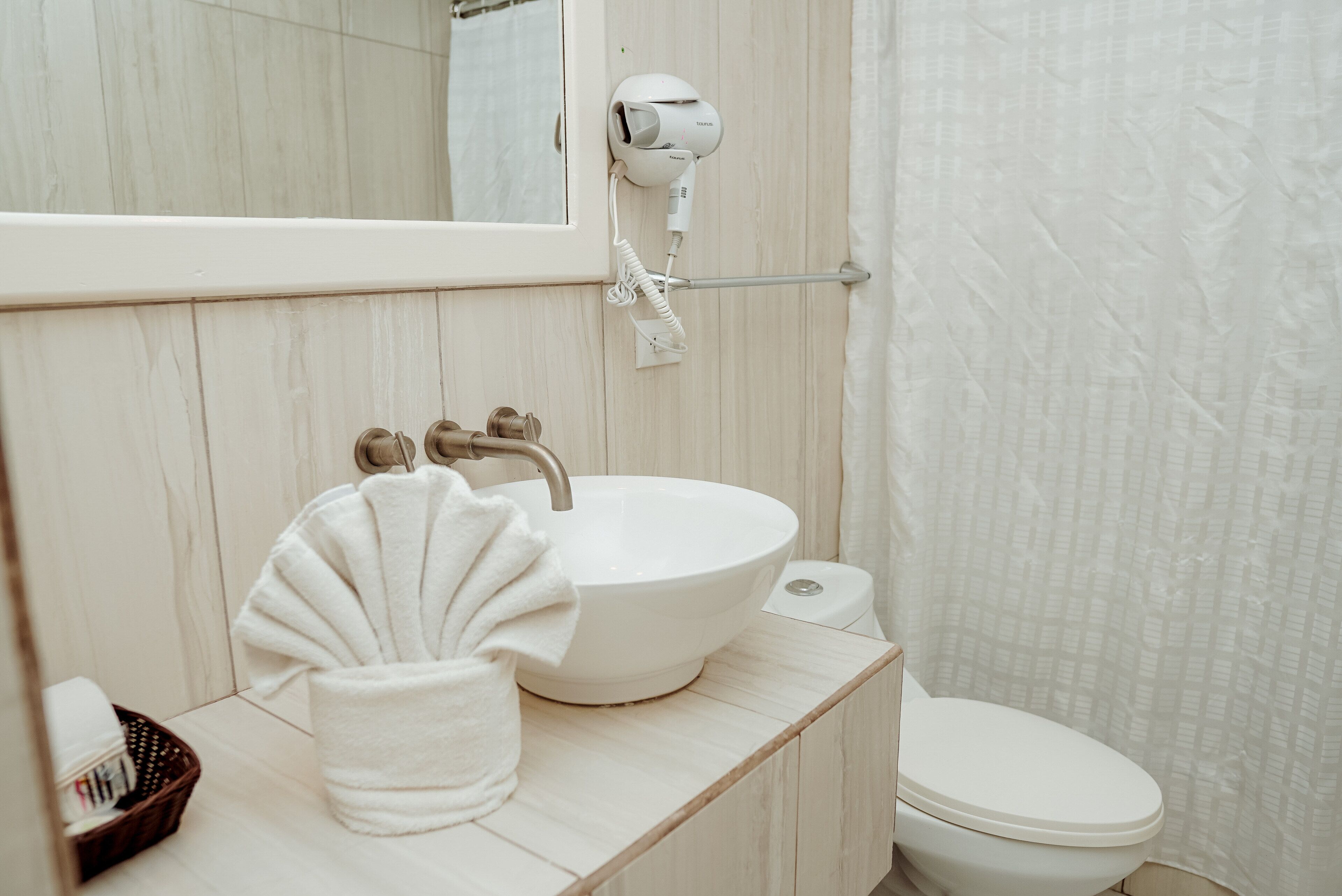 Une salle de bain avec un lavabo blanc, une serviette, un sèche-cheveux et des toilettes.