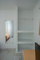 Una habitación con un armario blanco, un espejo y un banco de madera.