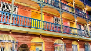 A multi-story building with balconies, a sign indicating a hotel, and parked vehicles. - Hotel Casona de La Isla (Flores)