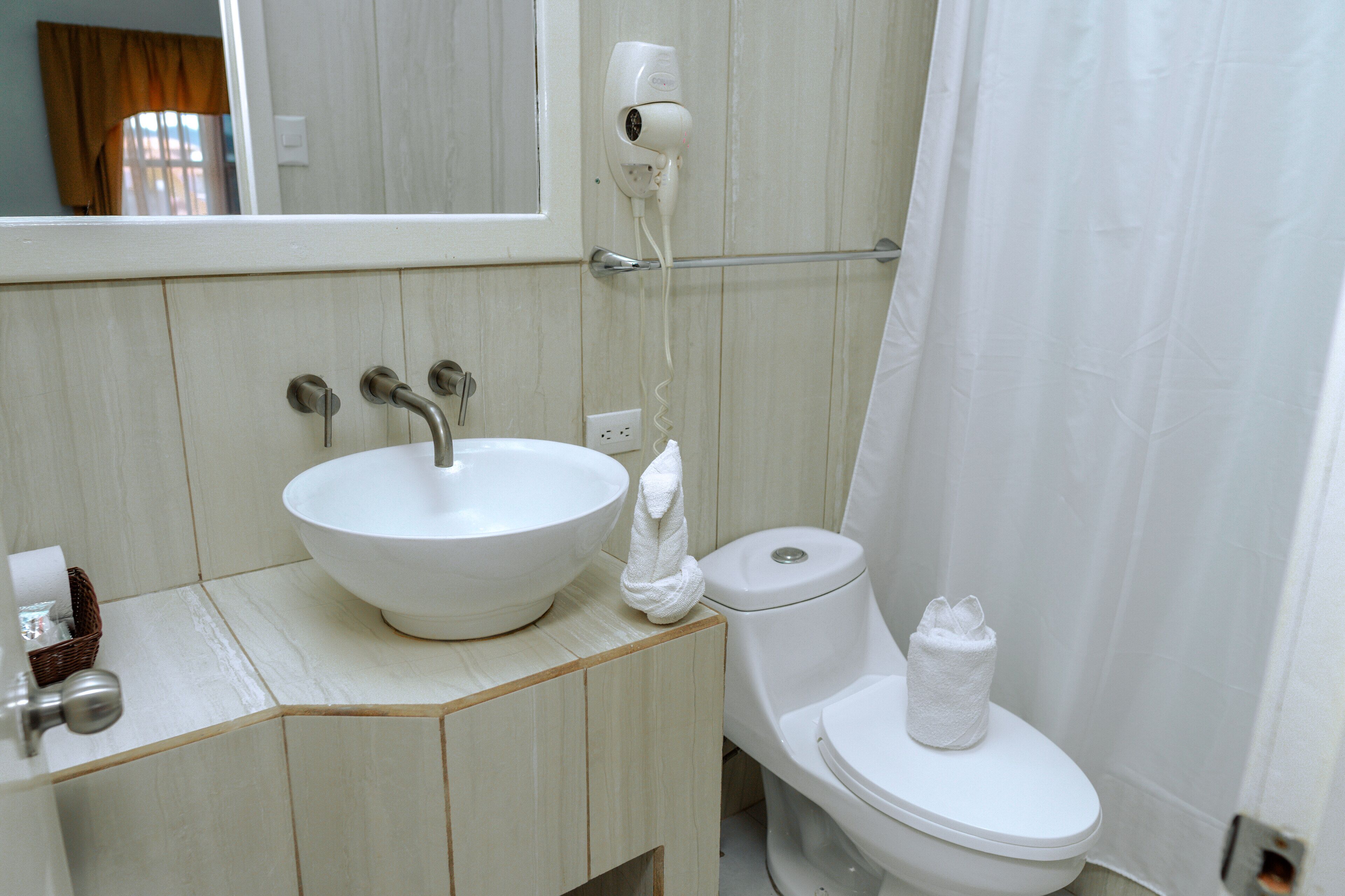 Une salle de bain avec un lavabo blanc, des toilettes et un rideau de douche.