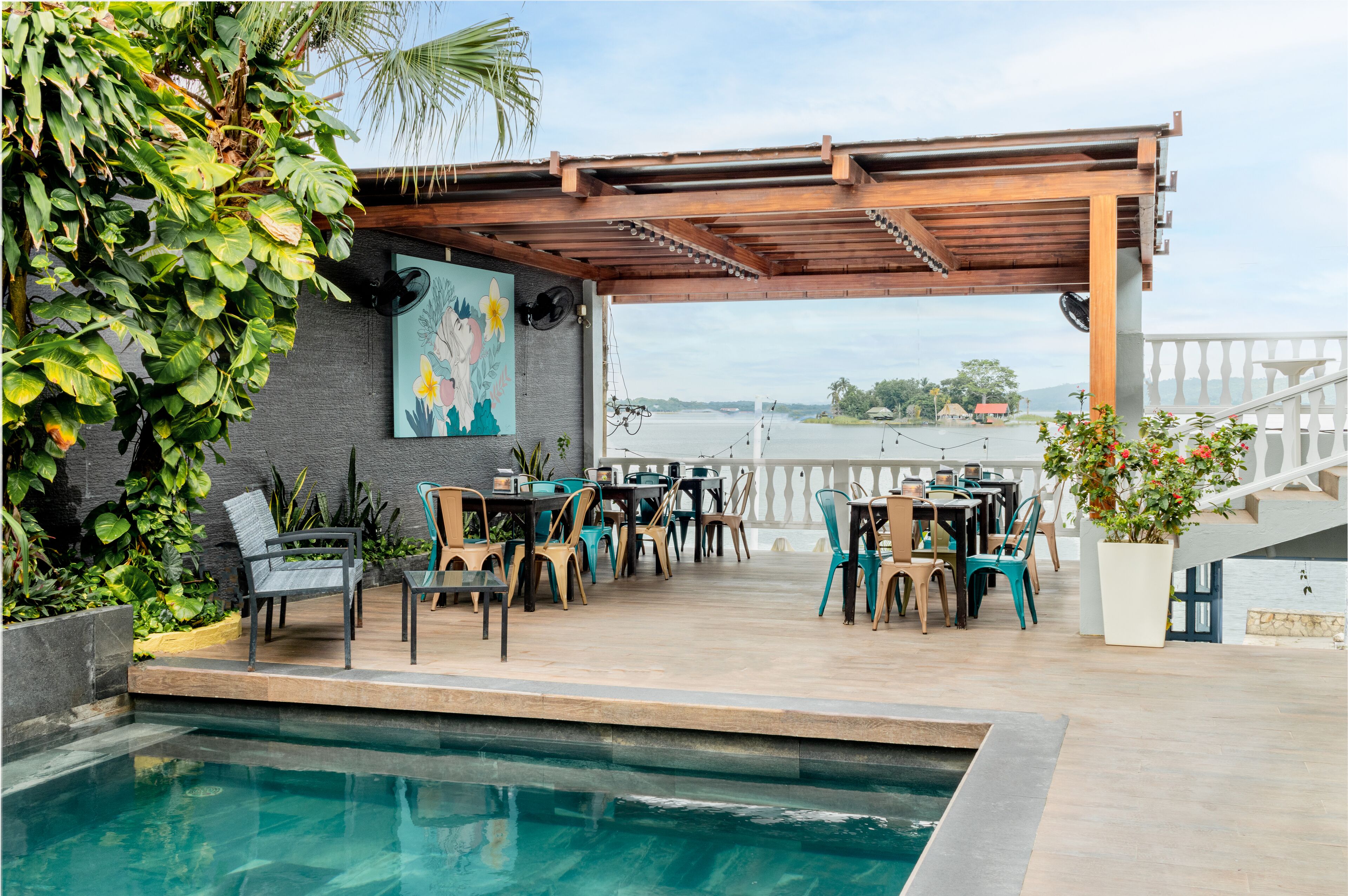 Eine Terrasss mit Pool, Holz-Pergola und Sitzbereich mit Stühlen und Tischen.