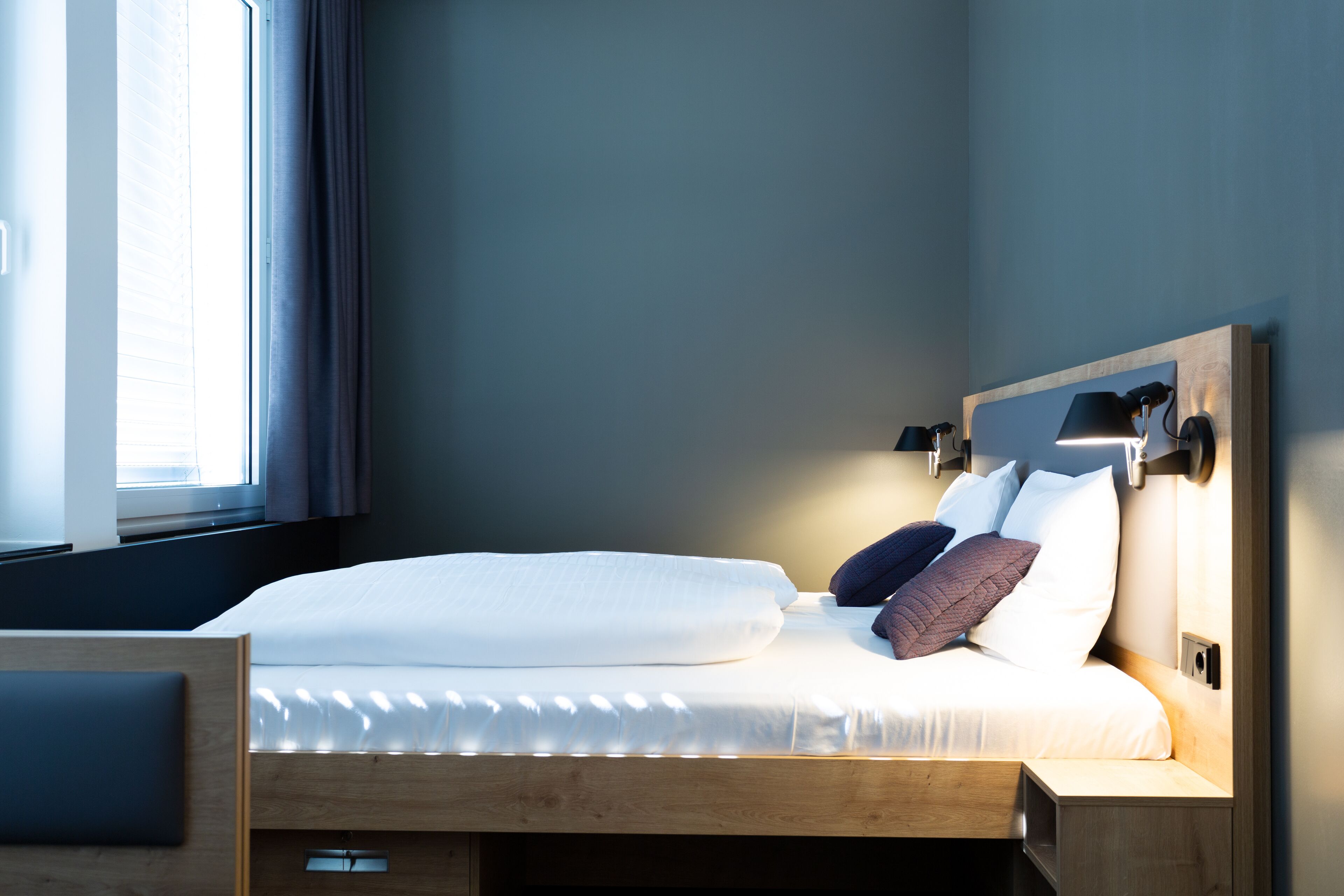 A modern bedroom with a wooden bed, a bedside table, and a nightstand.