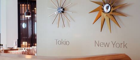 A bar area with a wooden bench and a wall-mounted clock labeled 'Tokyo' and 'New York'.