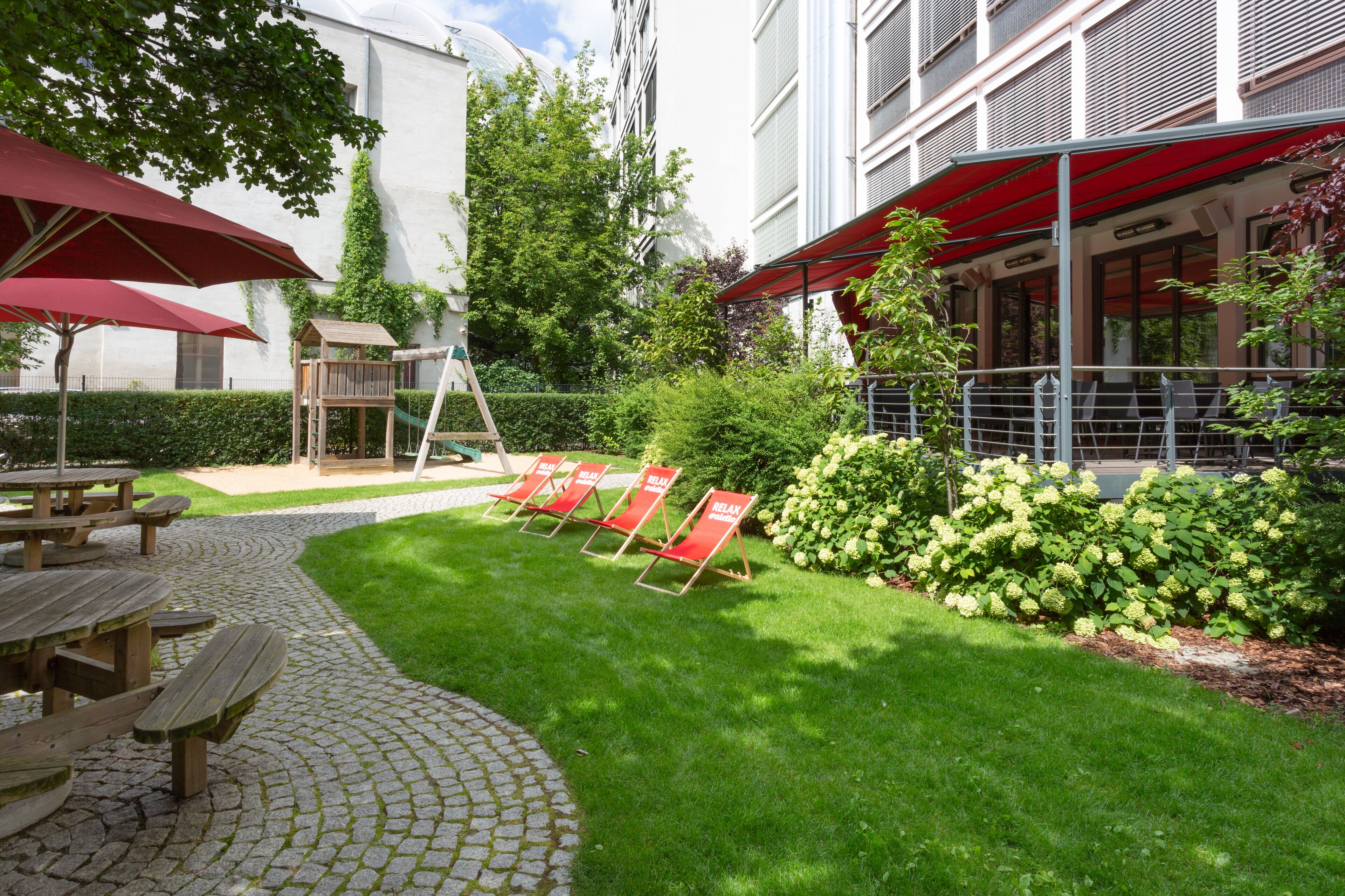 Un patio con mesas de picnic, sombrillas rojas y asientos al aire libre.
