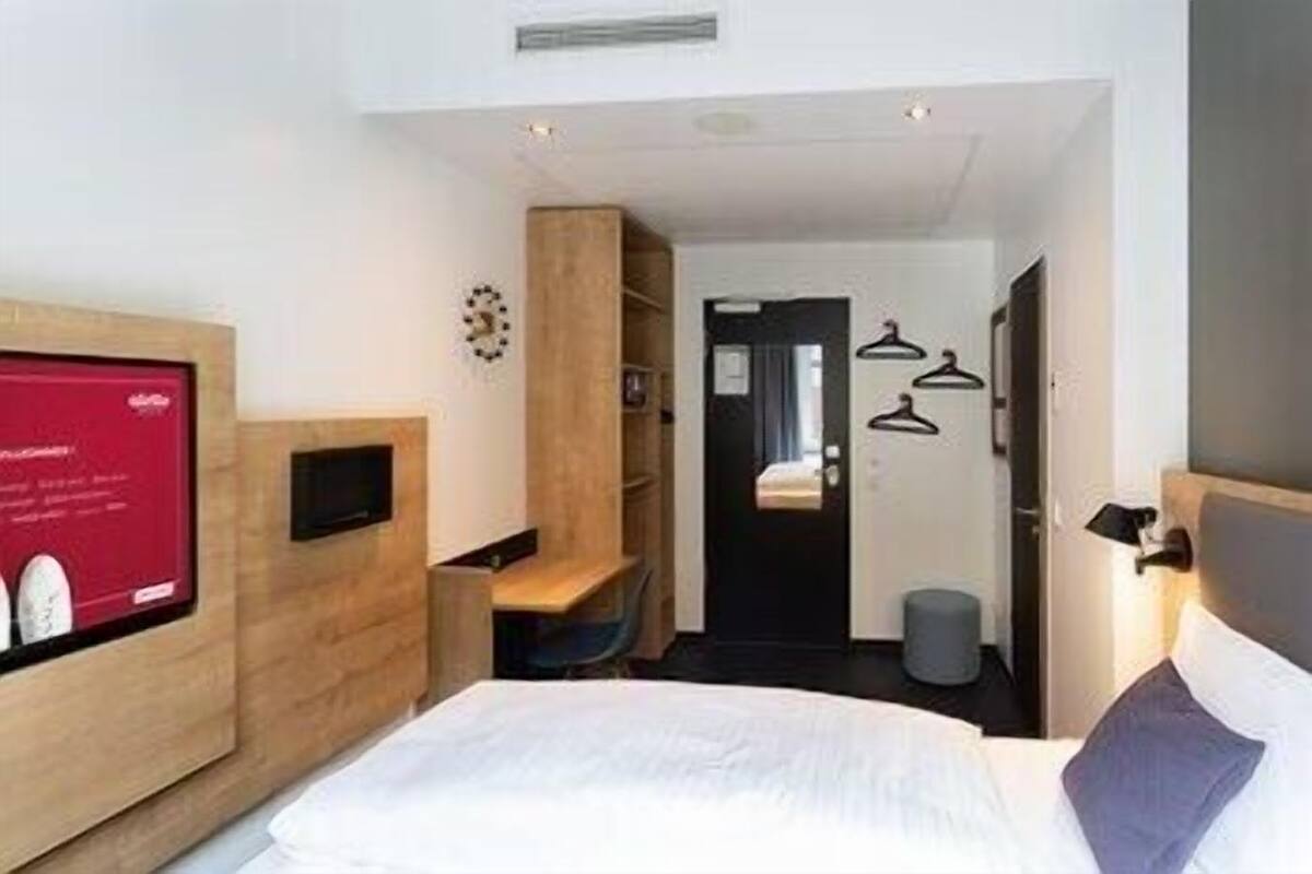 Une chambre d’hôtel équipée d’un lit, d’une télévision, d’un bureau et d’une armoire.