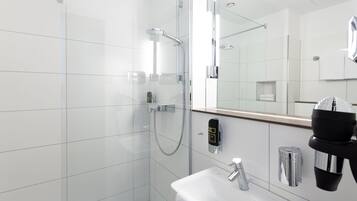 A modern bathroom with a glass-enclosed shower, a white sink, and a mirror.