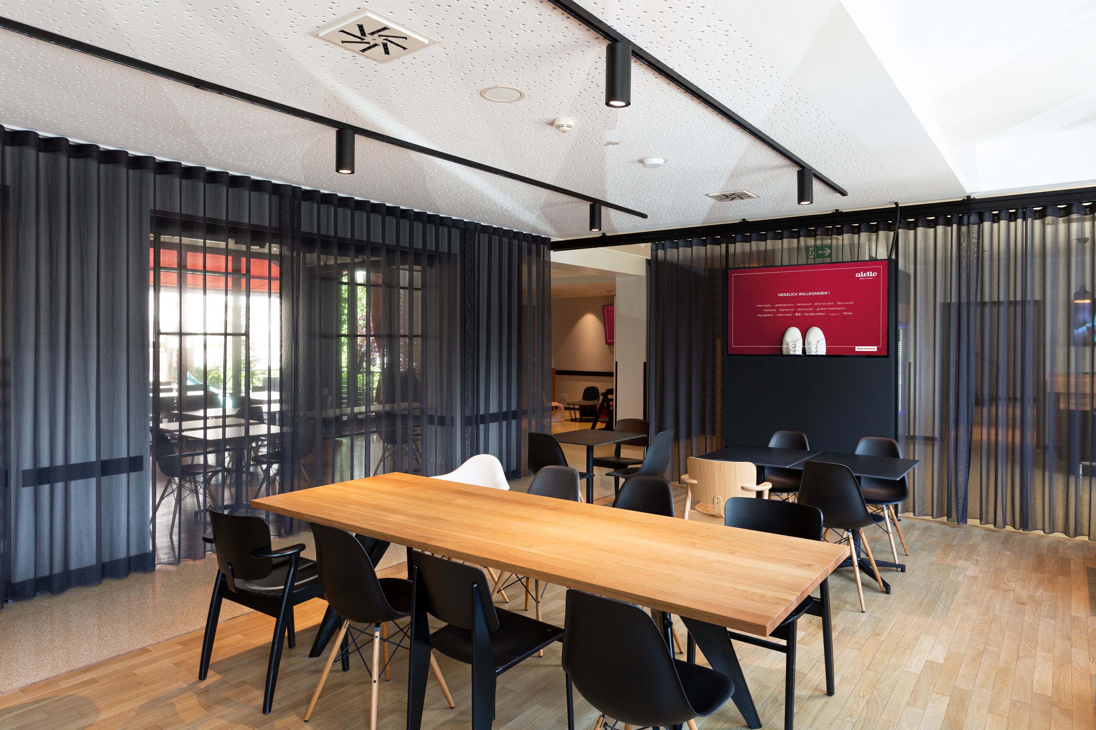 Uma sala de conferências moderna com uma mesa de madeira, cadeiras pretas e um sinal vermelho informativo.