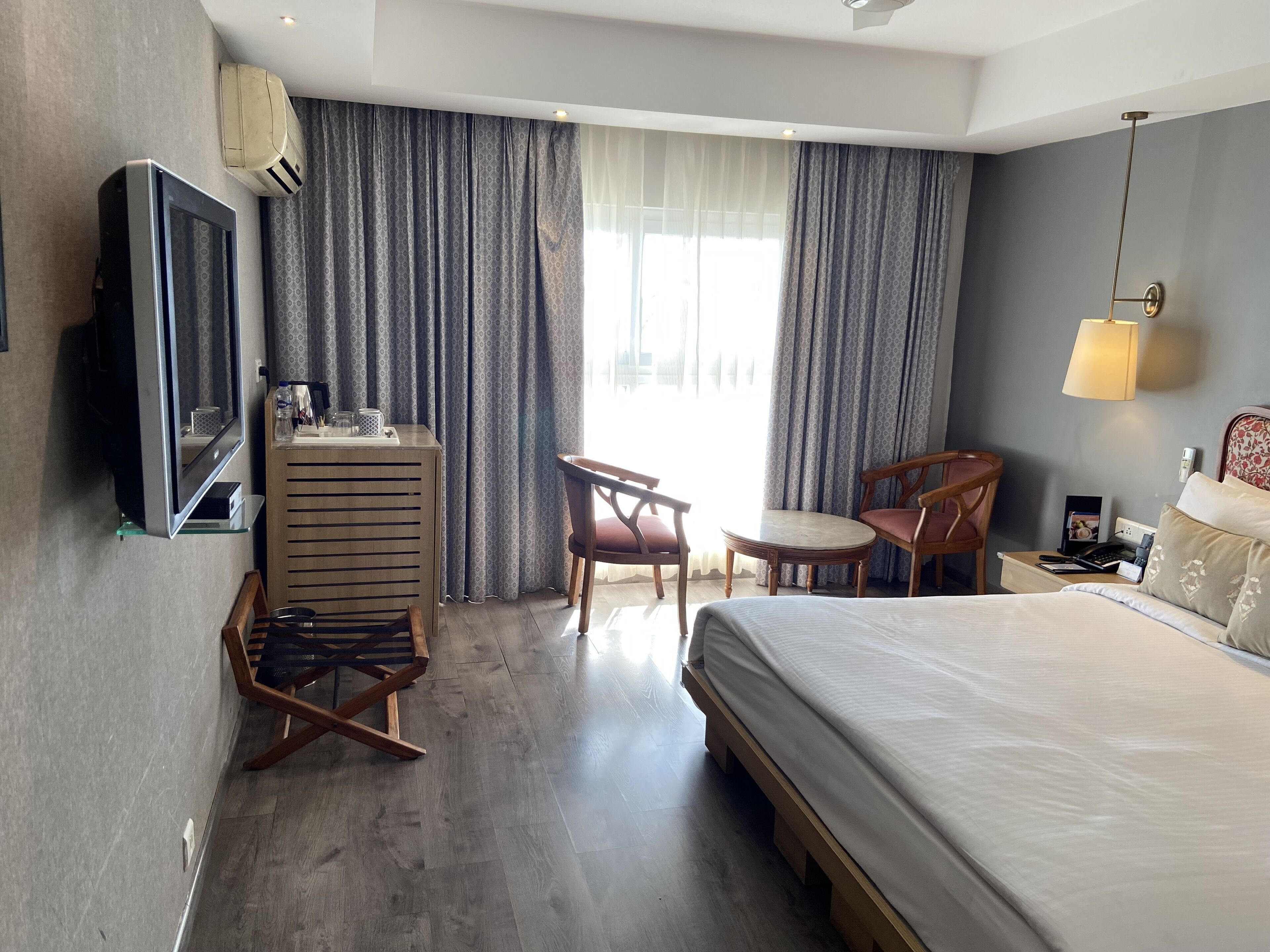 A hotel room with a bed, a desk, a chair, a TV, and a wardrobe.