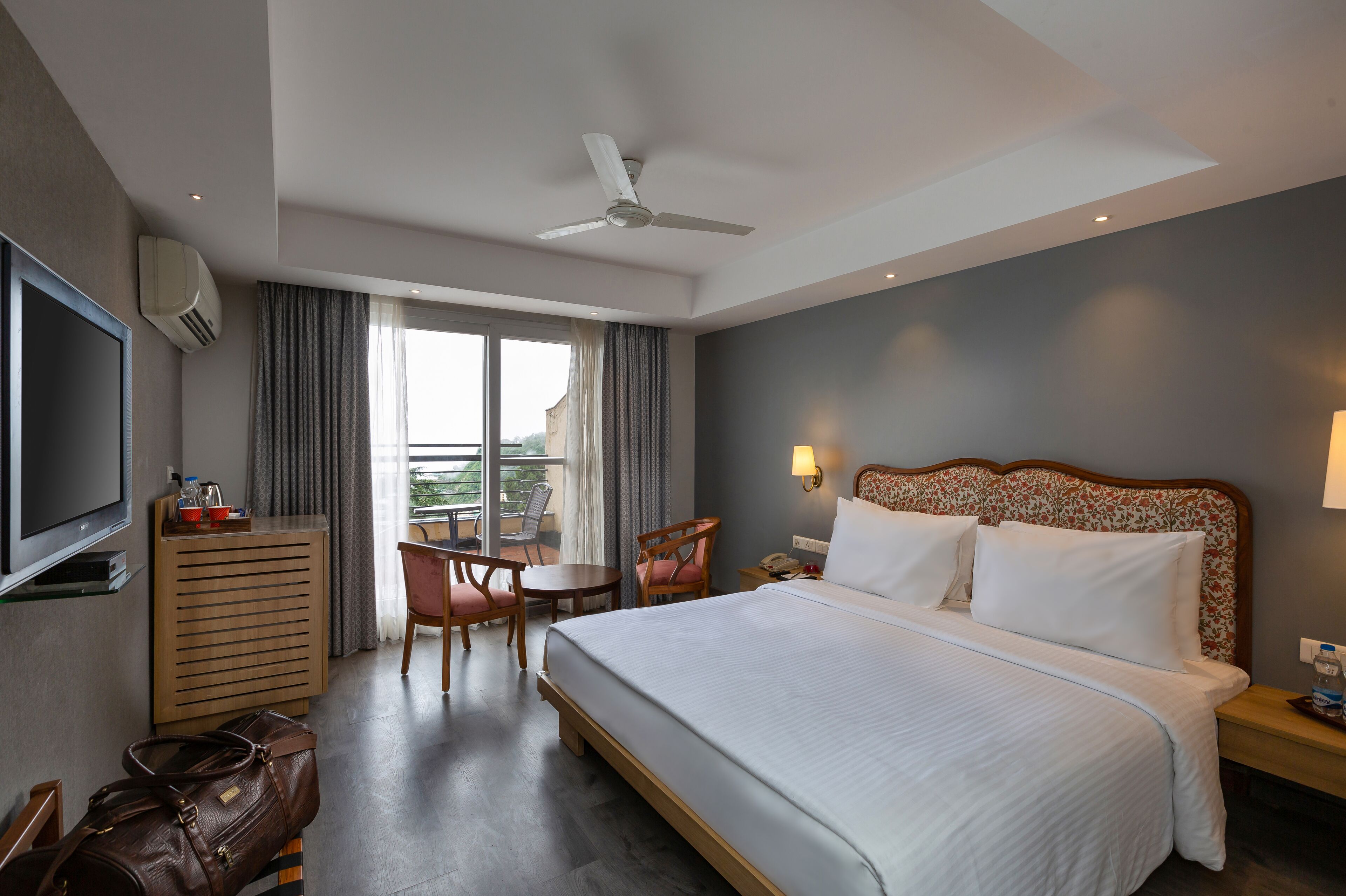 A hotel room with a bed, a TV, a desk, and a chair.