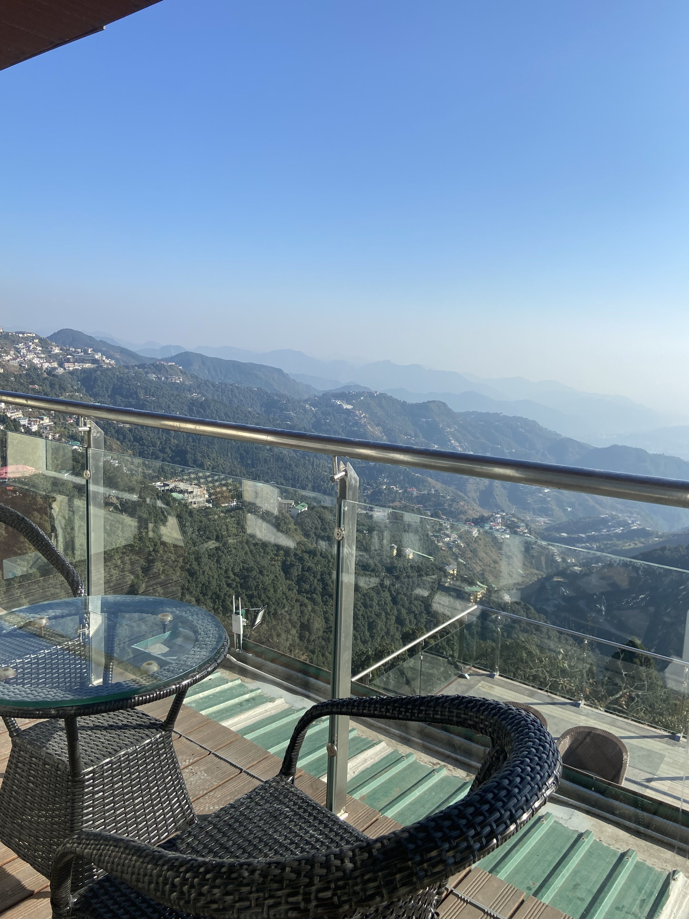A balcony with a glass railing overlooking a mountainous landscape.