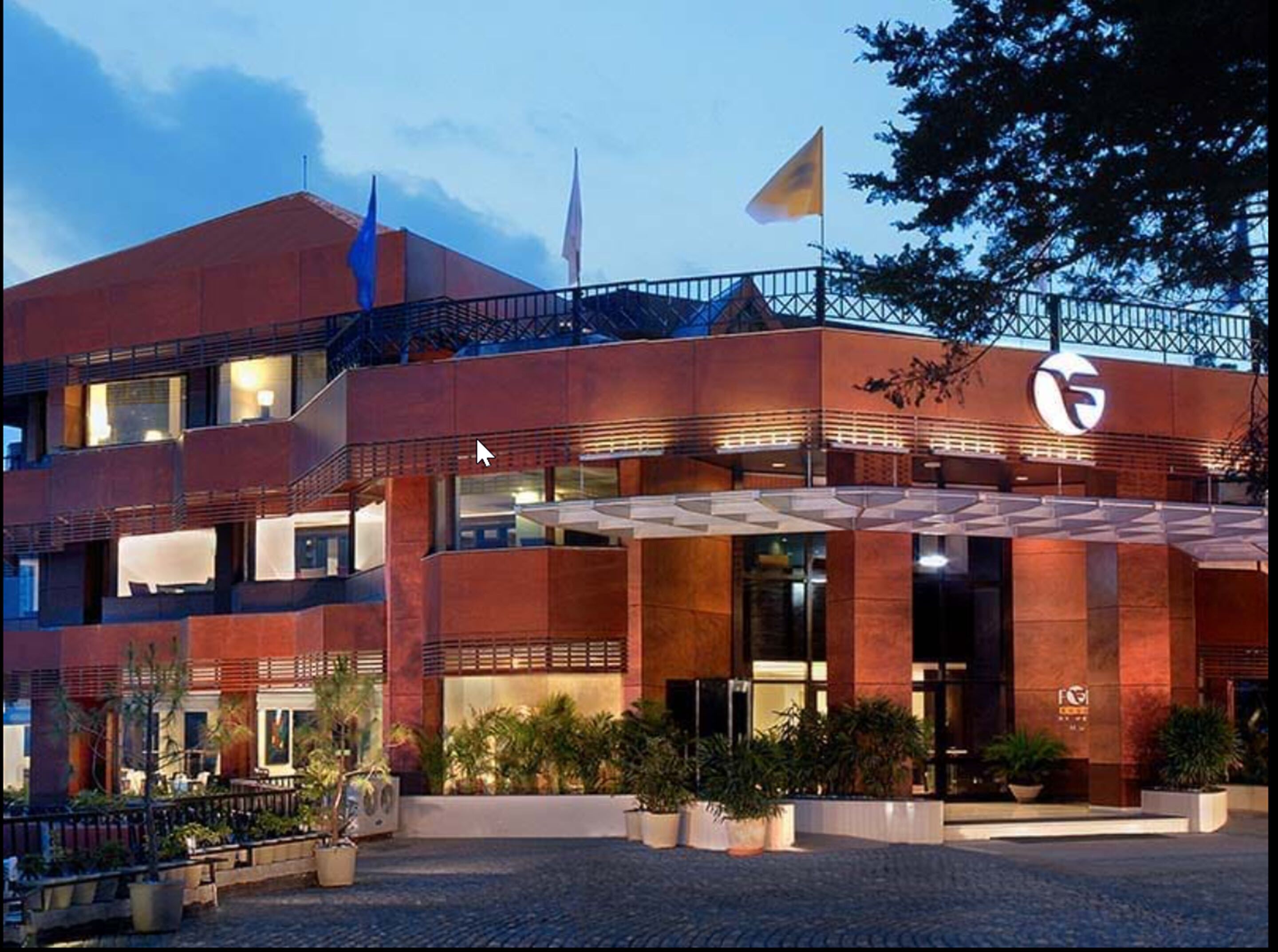 Un hotel moderno con fachada roja, varios balcones y una zona de entrada cubierta.