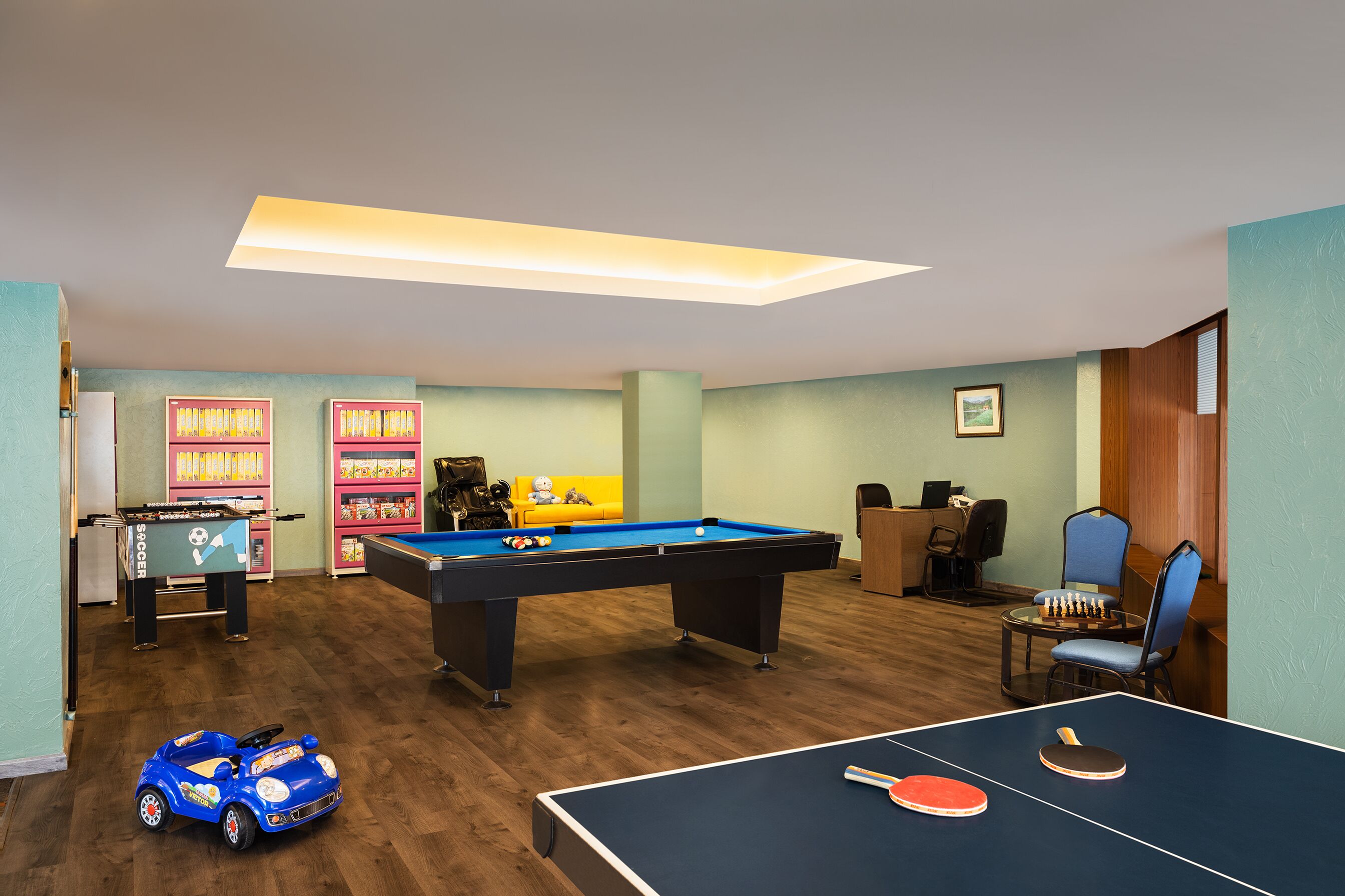 Una habitación con mesa de billar, mesa de ping pong y mesa de futbolín.