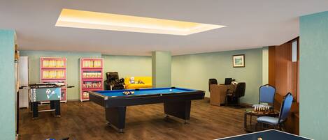 Una habitación con mesa de billar, mesa de ping pong y mesa de futbolín.