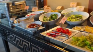 Een buffet met diverse eetopties, waaronder salades, fruit en een koffiehoek.
