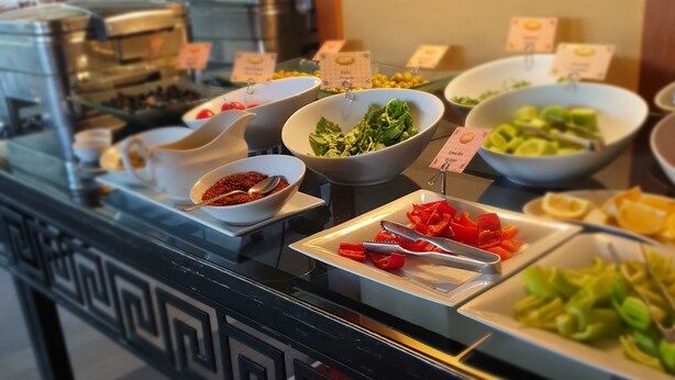 Een buffet met diverse eetopties, waaronder salades, fruit en een koffiehoek.