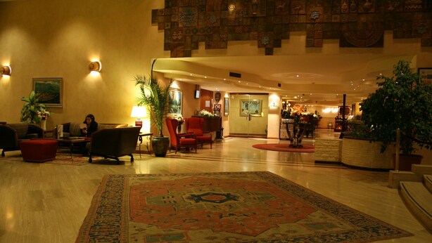 Un hall d’entrée spacieux, agrémenté d’un grand tapis décoratif, de sièges confortables et d’un espace d’accueil.