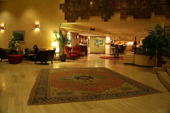 A spacious lobby with a large ornate rug, comfortable seating, and a reception area.