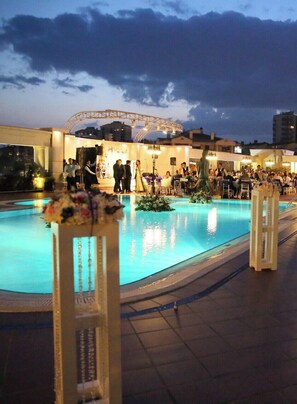 An outdoor pool area with a stage and seating for an event.