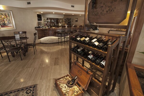 Une pièce spacieuse avec un meuble à vin en bois, un coin repas comprenant une table et des chaises, et un bar avec un comptoir et des étagères remplies de bouteilles.