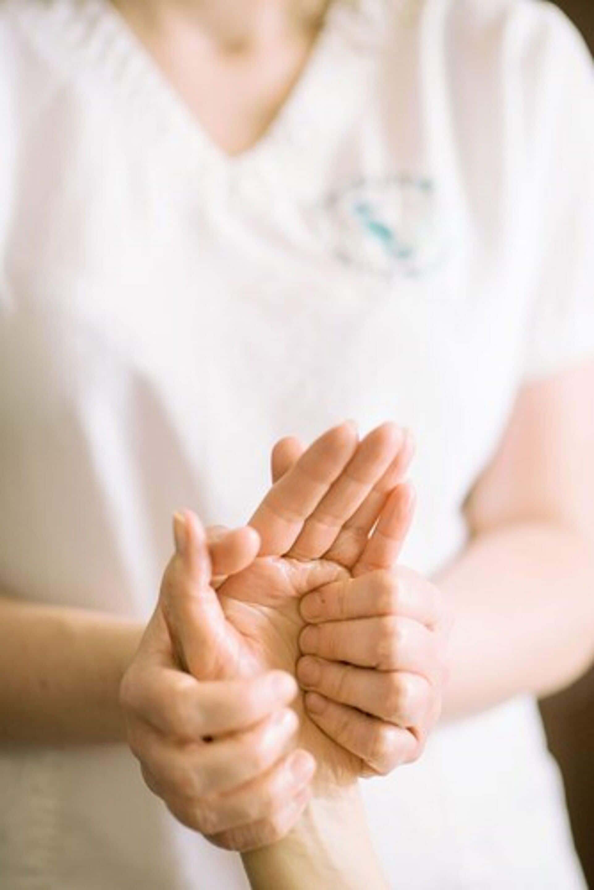 A person in a white shirt with a logo, holding hands with another person.