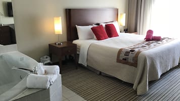 Ein Hotelzimmer mit einem großen Bett, einem separaten Badezimmer mit Badewanne und zwei Nachttischlampen.