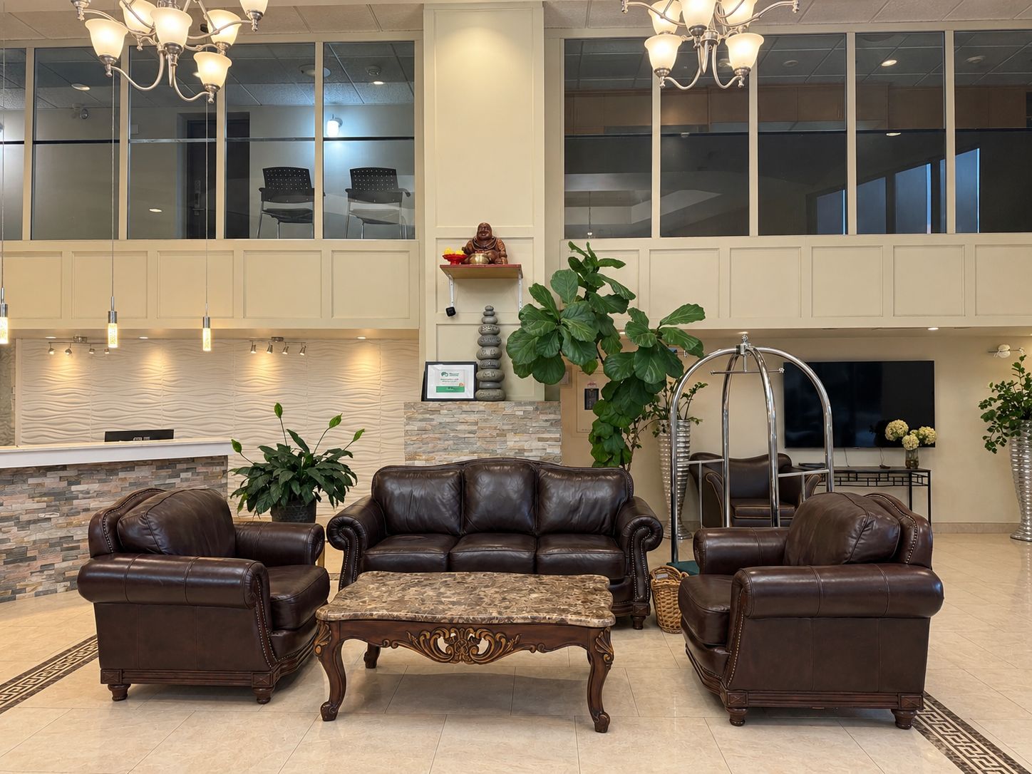 A spacious lobby with leather sofas, a marble coffee table, and a large potted plant.