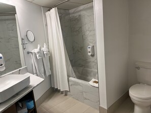 Ein modernes Badezimmer mit einer Marmordusche, Toilette, Waschbecken und einem Händetrockner.