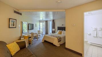 Une chambre d’hôtel comprenant un lit, un bureau, une chaise, une télévision et une salle de bain.
