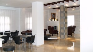 Eine moderne Hotelhalle mit Essbereich, Sitzgelegenheiten und einer Treppe zu einer oberen Etage.