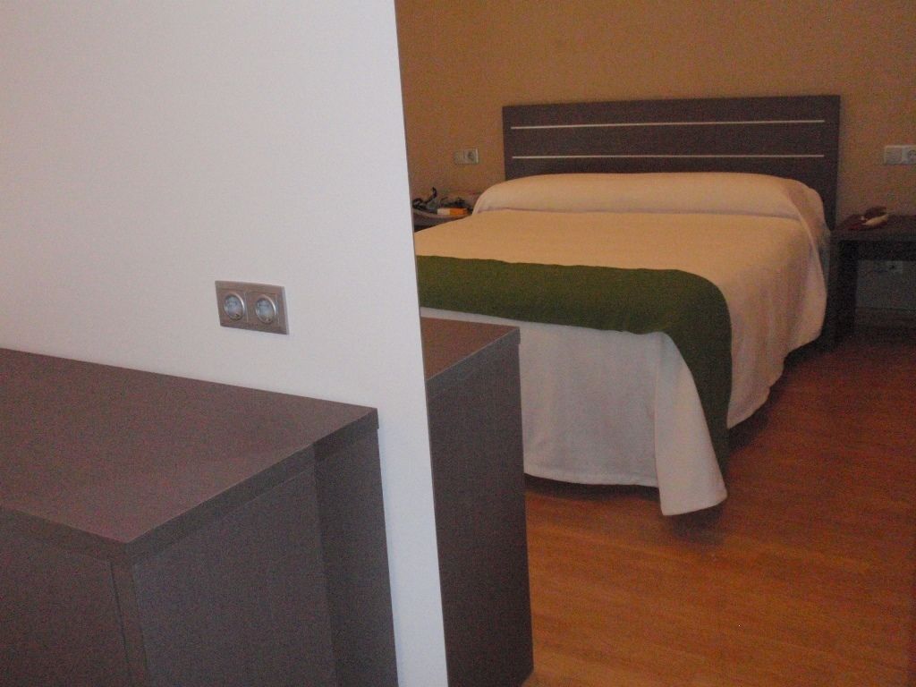 Une chambre d’hôtel avec un lit, des tables de chevet et un plancher en bois.