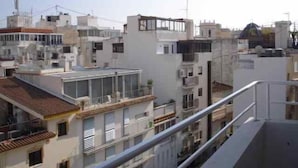 Ein mehrstöckiges Gebäude mit Balkonen und einer Dachterrasse.
