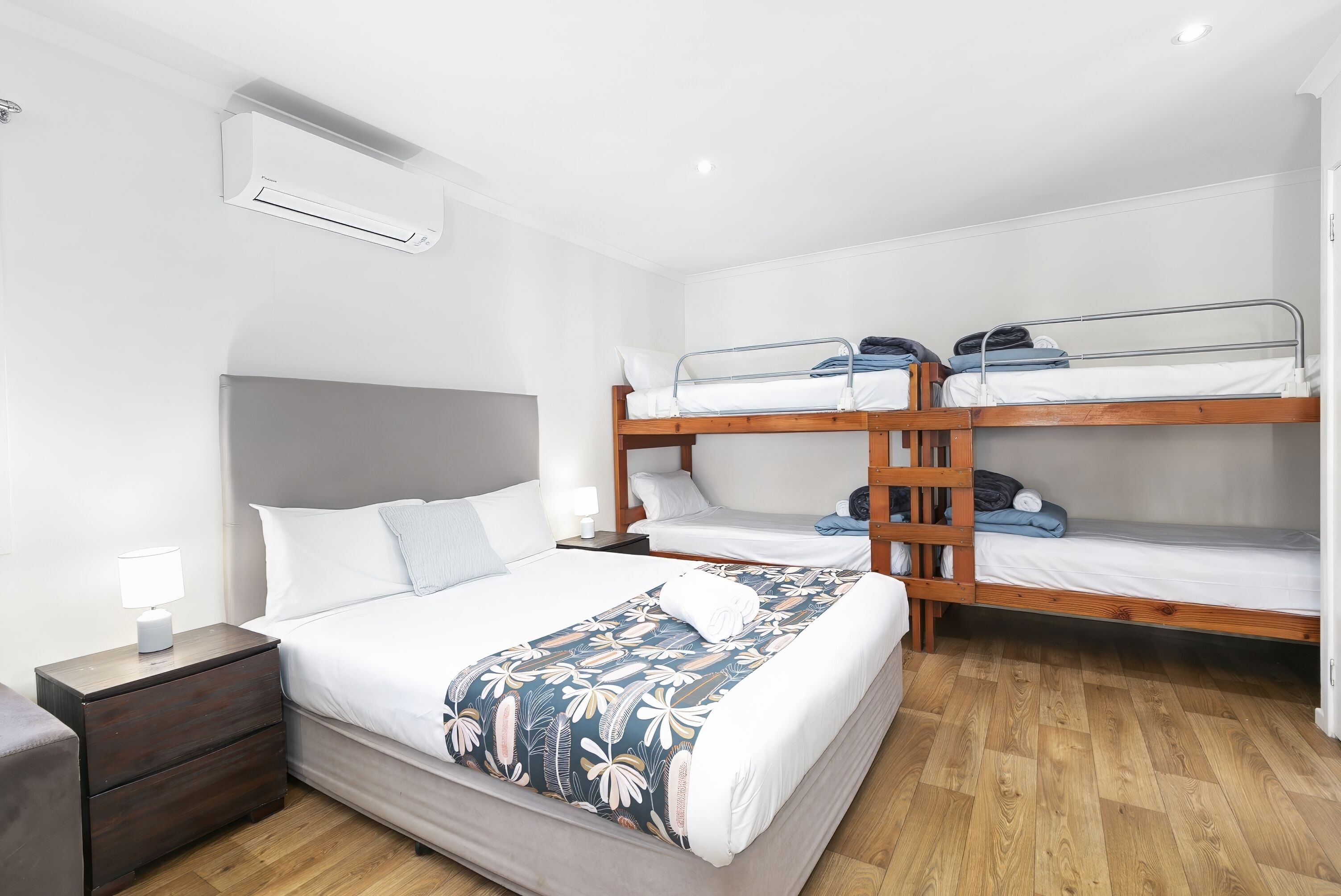 Ein Schlafzimmer mit einem Einzelbett, einem Nachttisch, einer Kommode und einem Etagenbett.