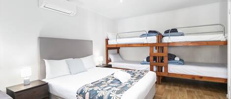 Ein Schlafzimmer mit einem Einzelbett, einem Nachttisch, einer Kommode und einem Etagenbett.