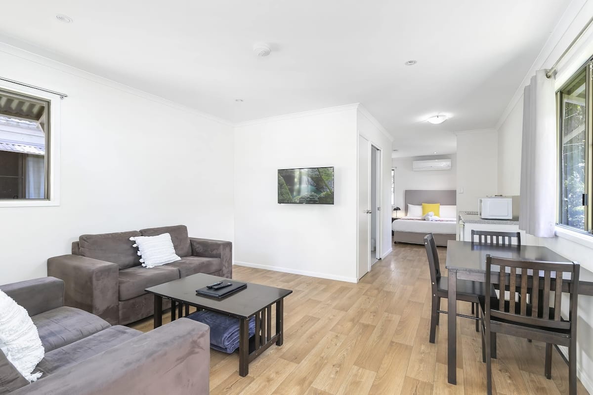 A modern living room with a sofa, coffee table, and dining area.