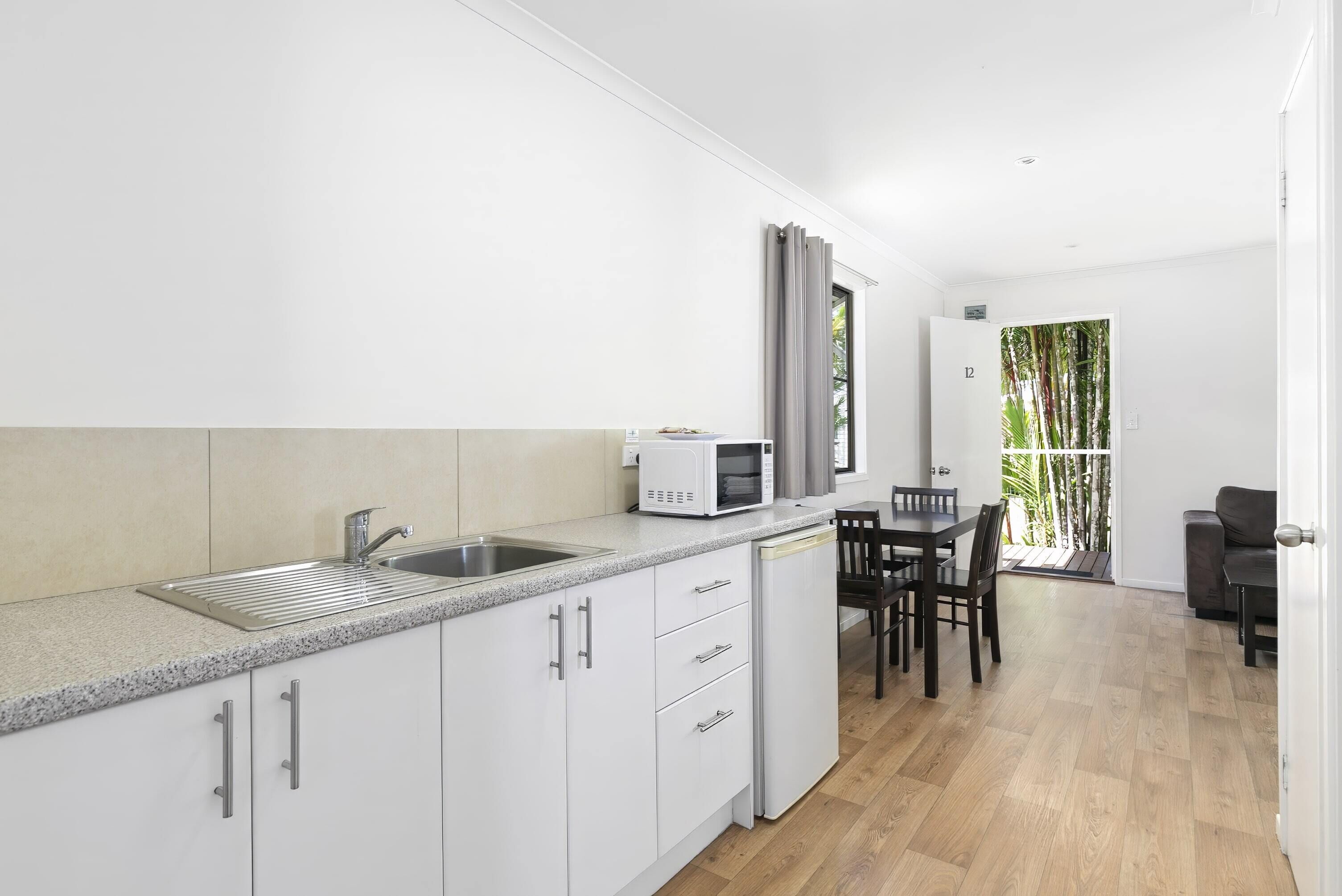 A modern kitchen with white cabinets, a granite countertop, and a built-in microwave.