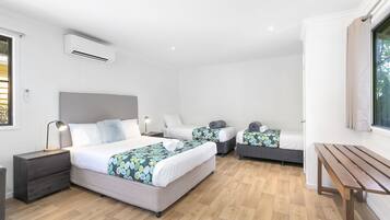 Moderni hotellihuone, jossa on suuri sänky, pienempi sänky, työpöytä ja penkki.