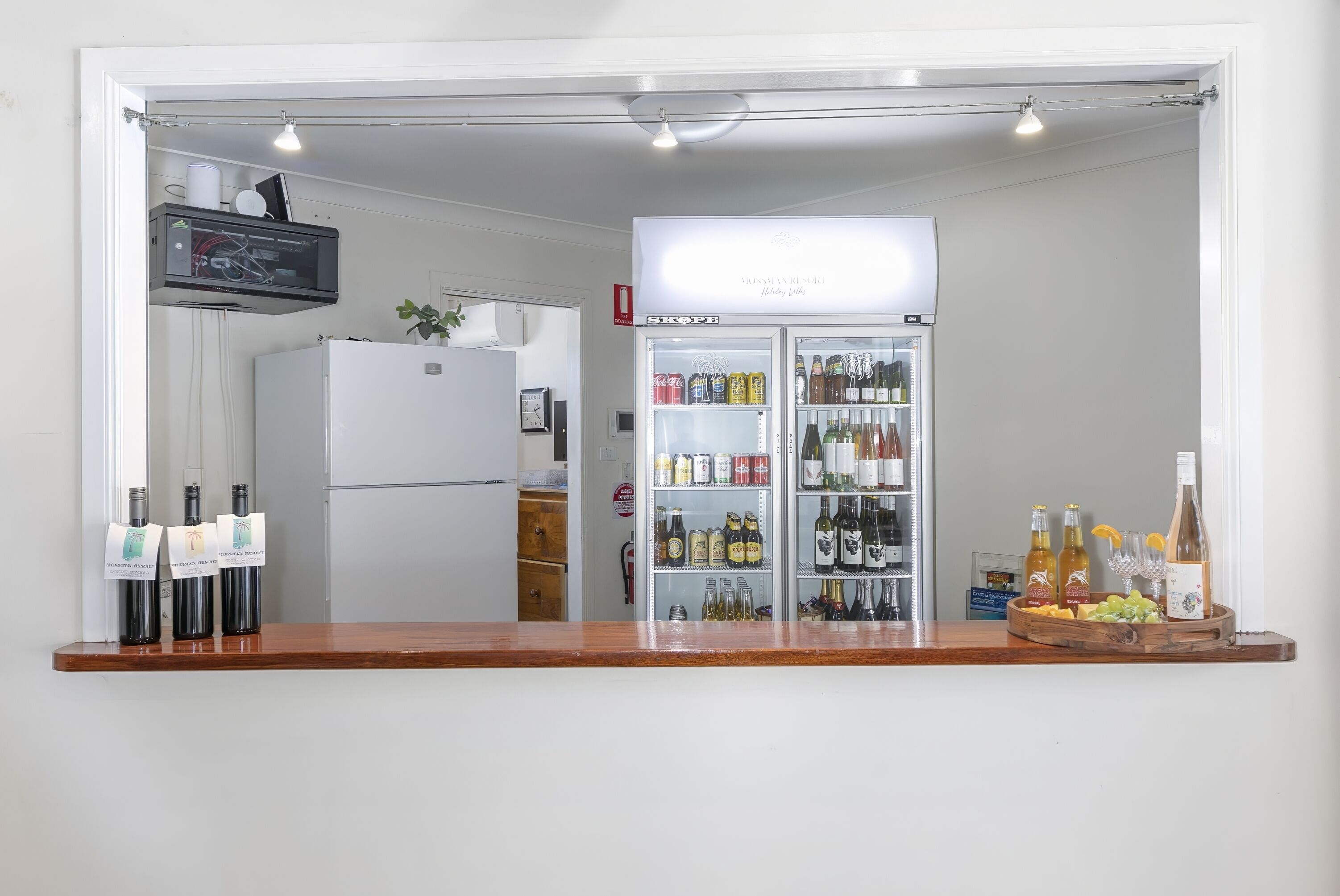 A bar area with a refrigerator, a minibar, and a variety of bottles and glasses.