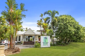 Un resort con área de recepción, palmeras y un letrero que dice 'Mossman Resort'.
