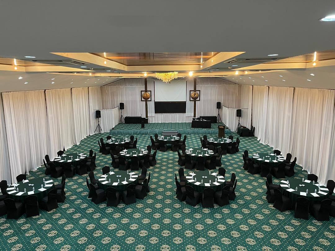 A conference room with a long table and multiple smaller tables, all equipped with chairs and nameplates.