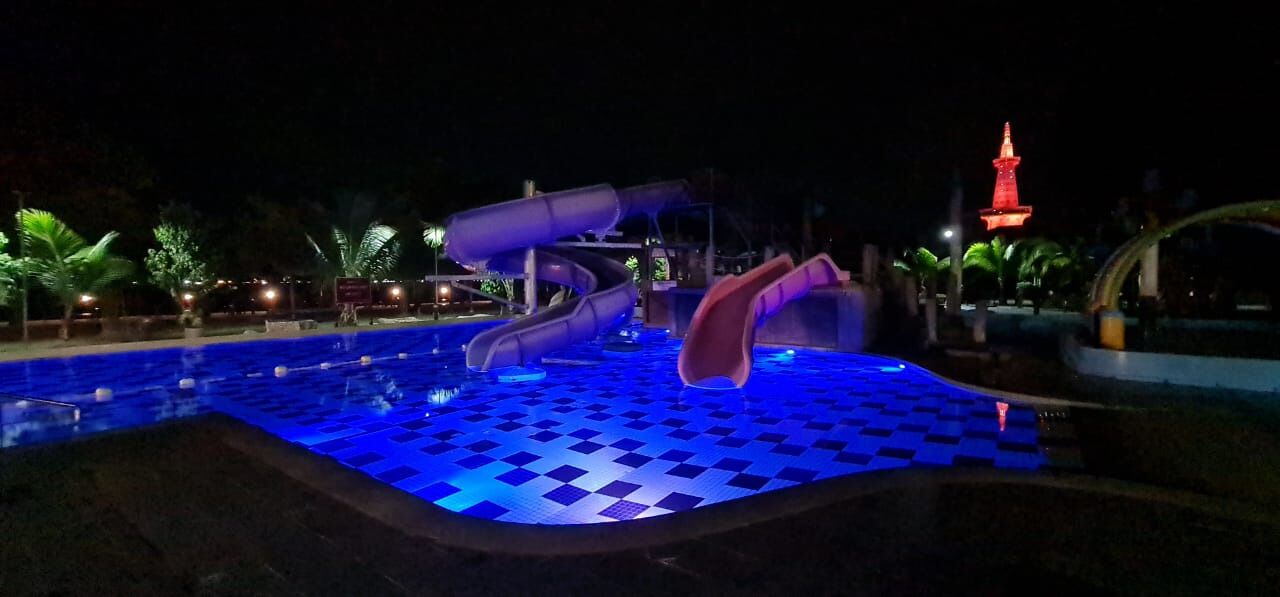 A water park at night with slides and a checkered pool floor.