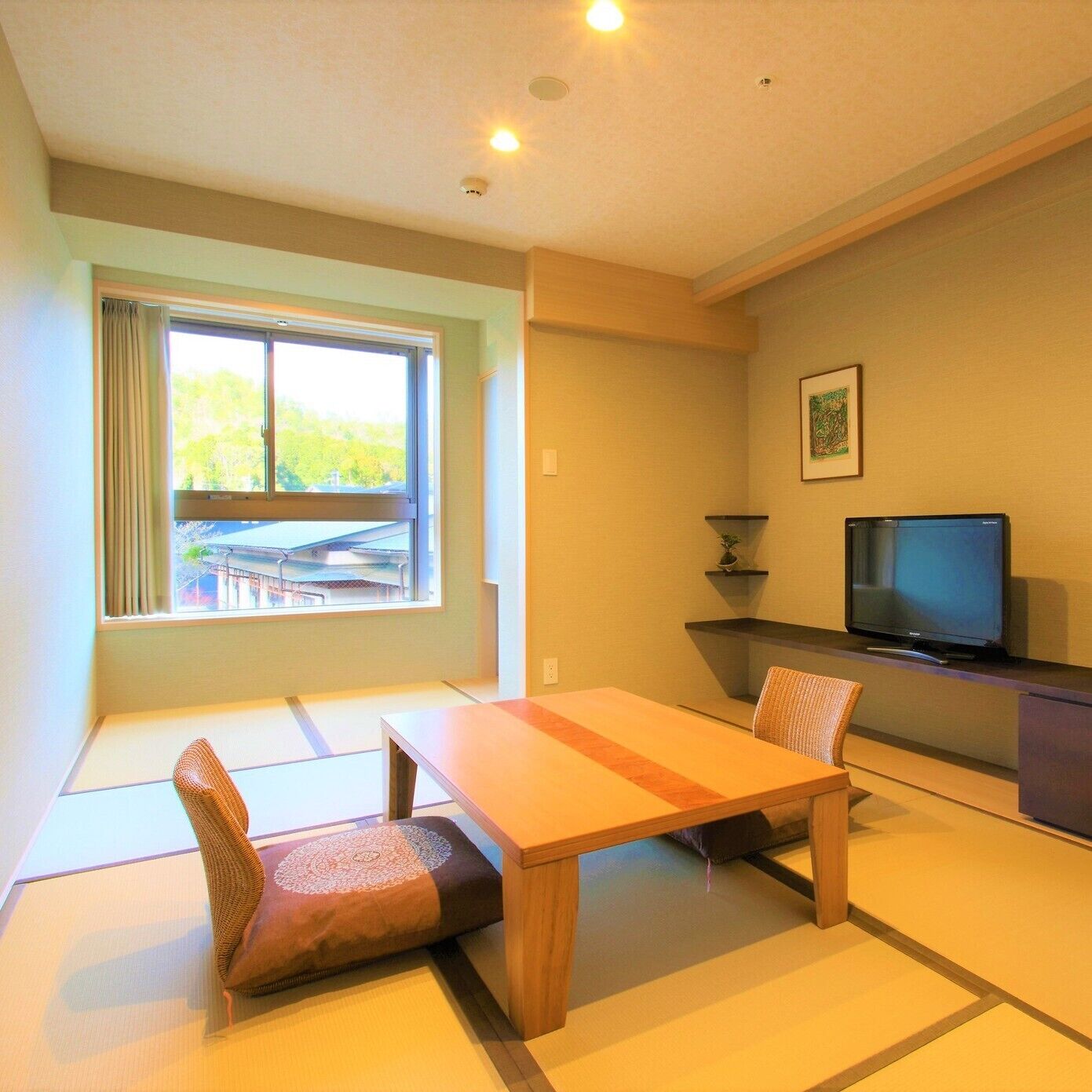 A room with tatami mats, a low table, a television, and a window with curtains.