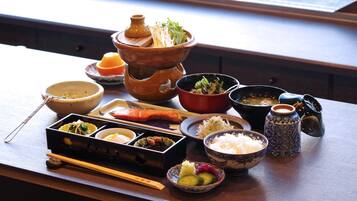 Una comida tradicional japonesa con diversos platos y utensilios sobre una mesa de madera.
