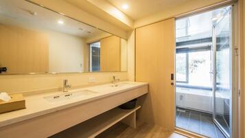A modern bathroom with two sinks, a large mirror, and a sliding glass door leading to a balcony.