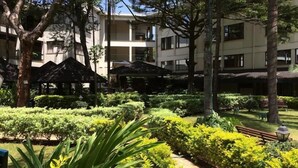 A courtyard with neatly trimmed hedges, a bench, and a gazebo. - Jacaranda (Nairobi)