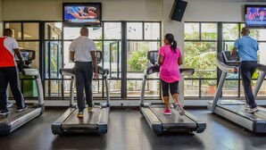 A gym with treadmills, large windows, and TVs displaying news. - Jacaranda (Nairobi)